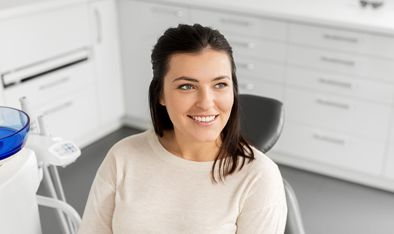 Woman sitting in dental exam chair and smiling